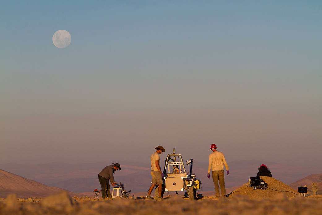 The Moon rises over the ARADS team, working with its prototype Mars rover in the Atacama Desert.Two members of the ARADS science