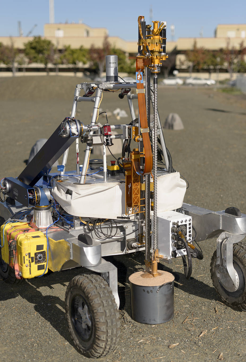 The ARADS rover is seen with its drill position over a large pot of simulated desert soil.