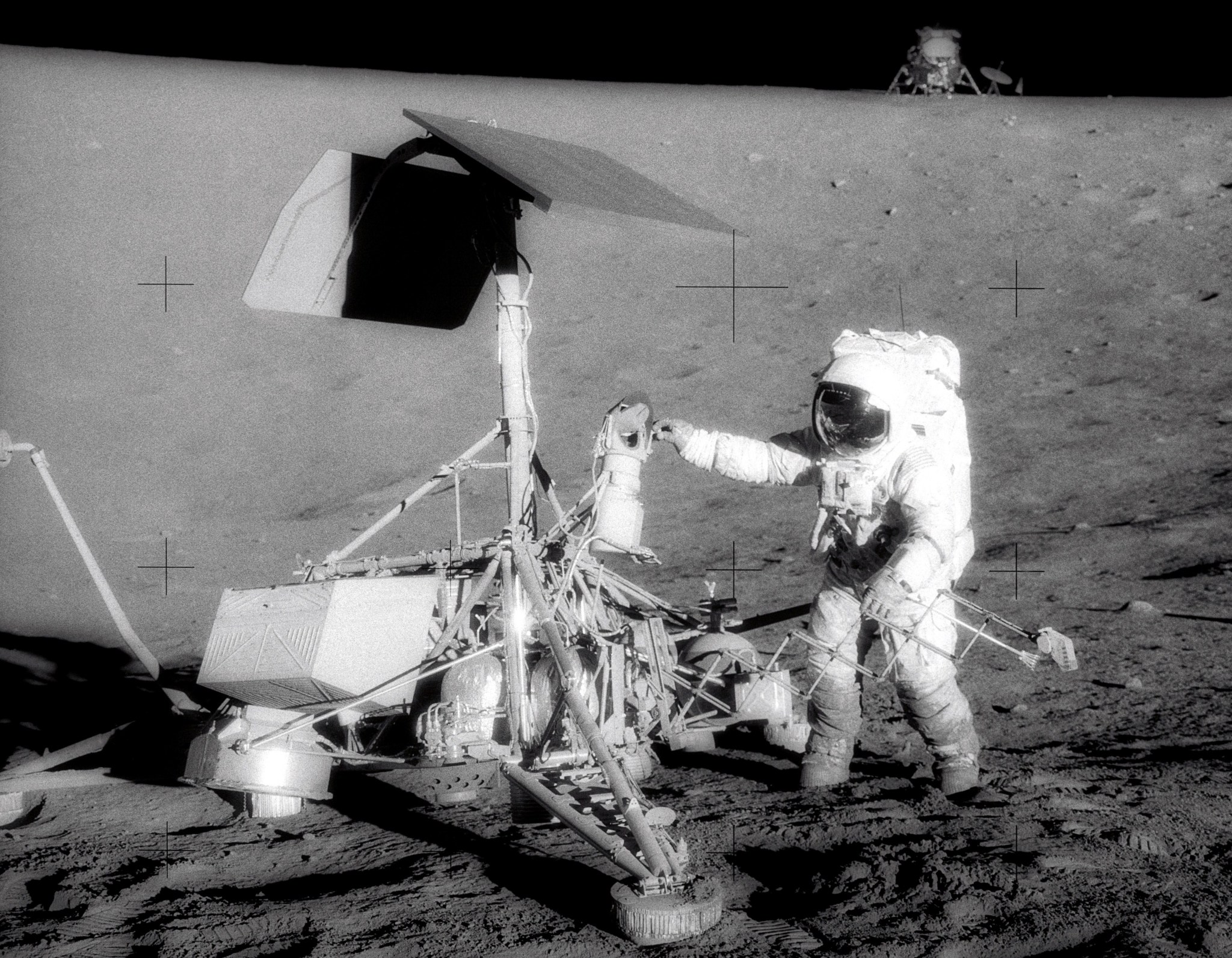 Astronaut on moon inspecting equipment.