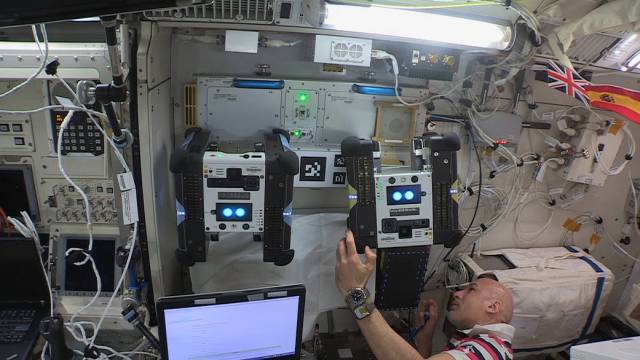 European Space Agency astronaut Luca Parmitano places the second Astrobee robot, named Honey, on Astrobee’s docking station .