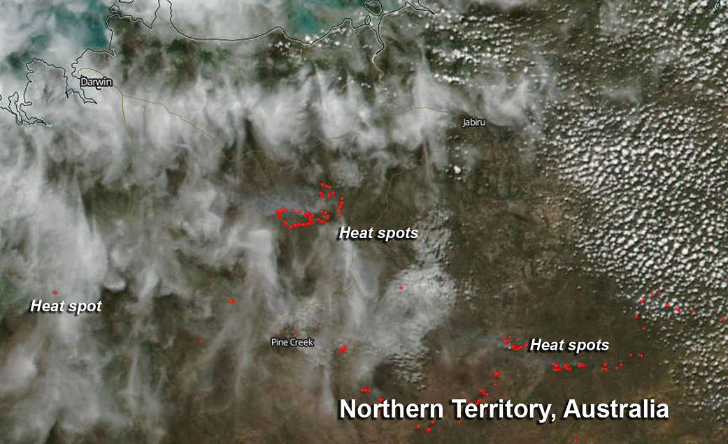 satellite image of land with clouds, smoke and red dots for fires