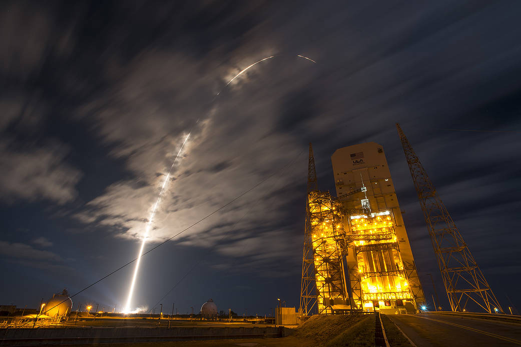 Arc of launch into clouds at nighttime with United Launch Alliance tower at right