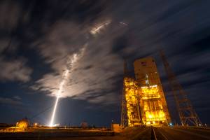 Arc of launch into clouds at nighttime with United Launch Alliance tower at right