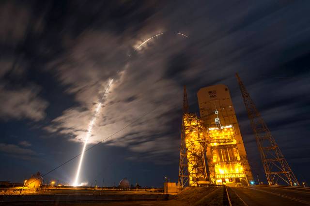 Arc of launch into clouds at nighttime with United Launch Alliance tower at right