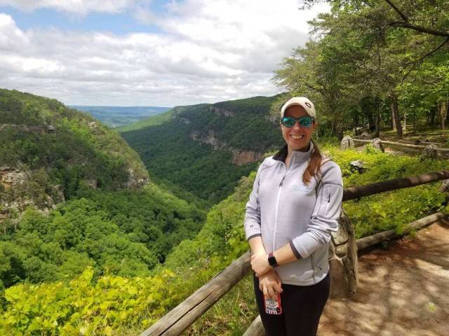 Remote Sensing Scientist Dr. Sarah Bang standing in front of a view of a forested mountain range called "Cloudland Canyon."