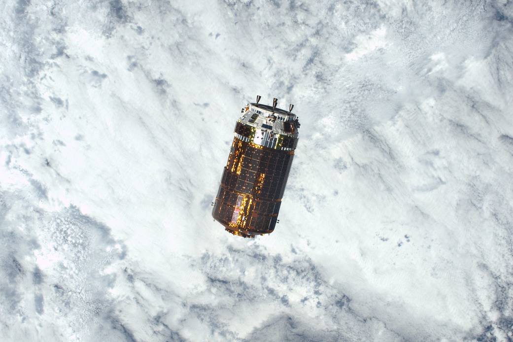 Cargo spacecraft approaches with clouds and Earth visible below
