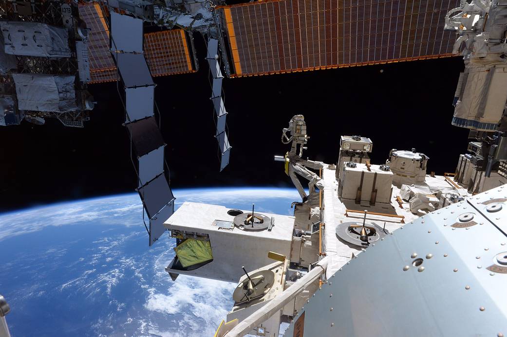 View of Earth from space station with solar arrays and station modules visible