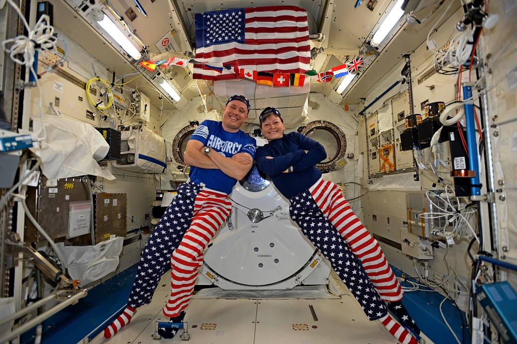 Astronauts Fischer and Whitsun wearing stars and stripes pose for a photo inside space station module