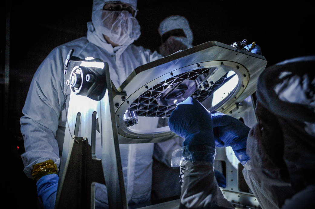 NASA engineers inspect a new piece of technology developed for the James Webb Space Telescope, a micro shutter array