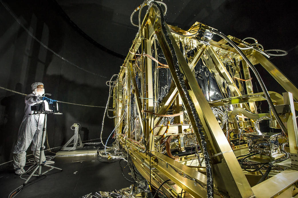 Dressed in a clean room suit, NASA photographer Desiree Stover shines a light on the Space Environment Simulator's Integration F