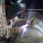 A welder at works on a portion of piping to be installed on the A-1 Test Stand for RS-25 rocket engine testing.