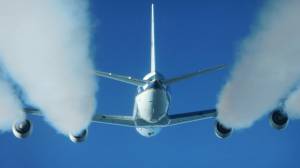 Large jet flying overhead with white contrails from engines