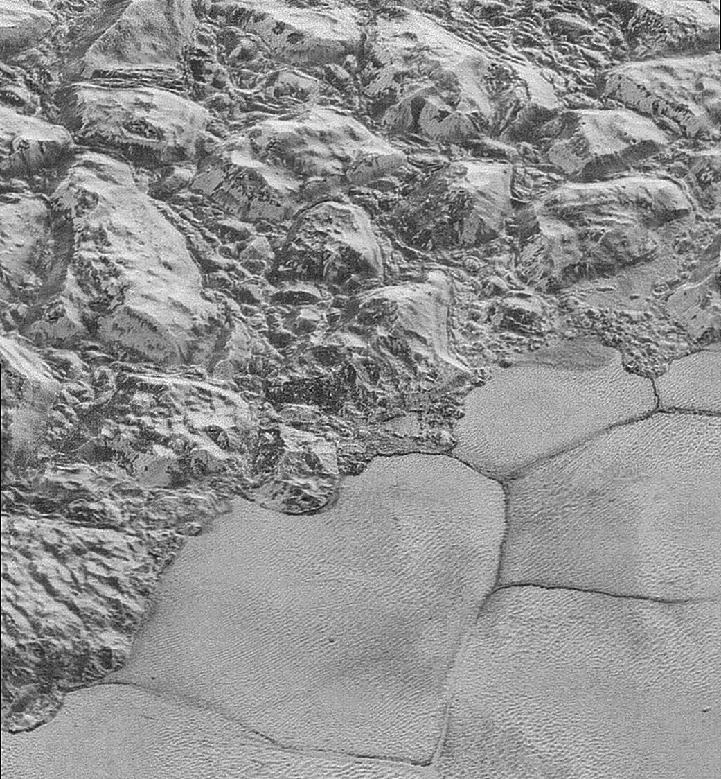 Image of dunes of methane ice on Pluto. Upper left: mountainous region adjacent to a plain. Lower right: patterns of dune.
