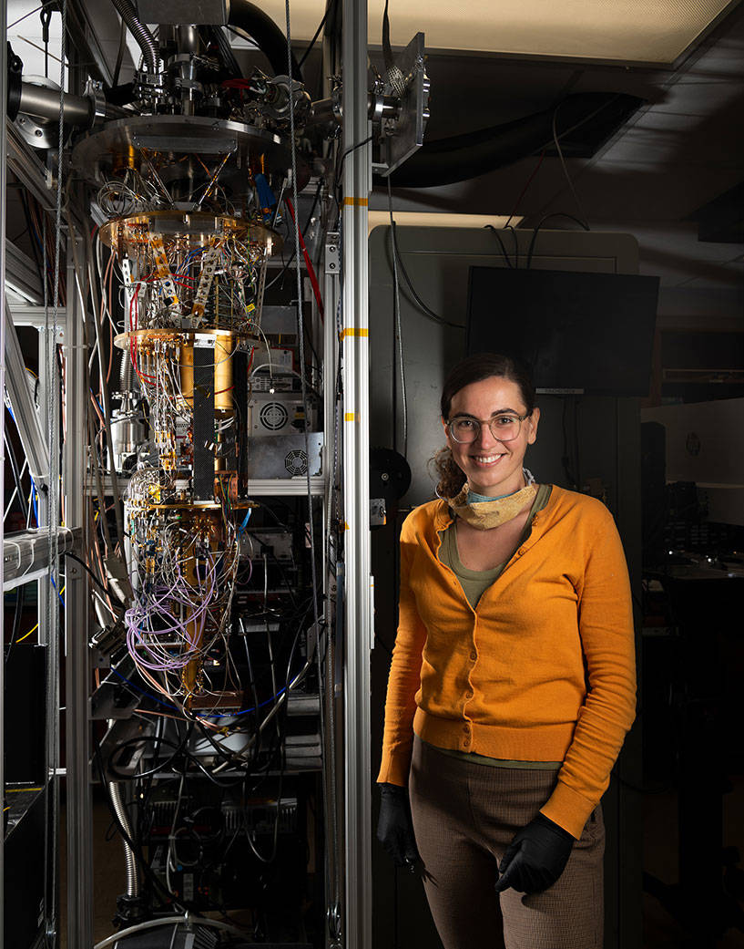 Ioana Craiciu, who led the study, stands next to the cryostat that was used to test PEACOQ