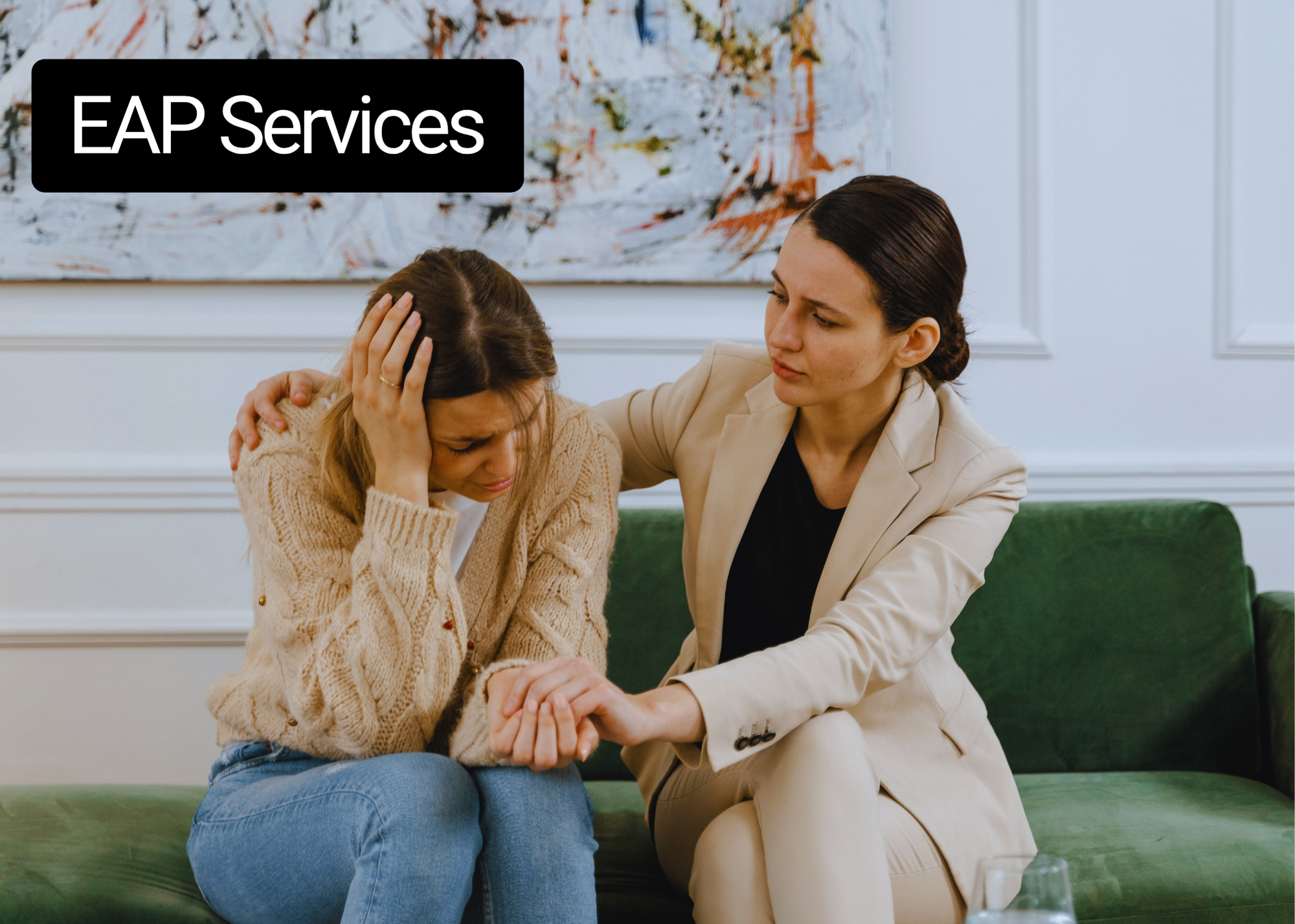 Two women sitting on a couch, one is comforting the other.