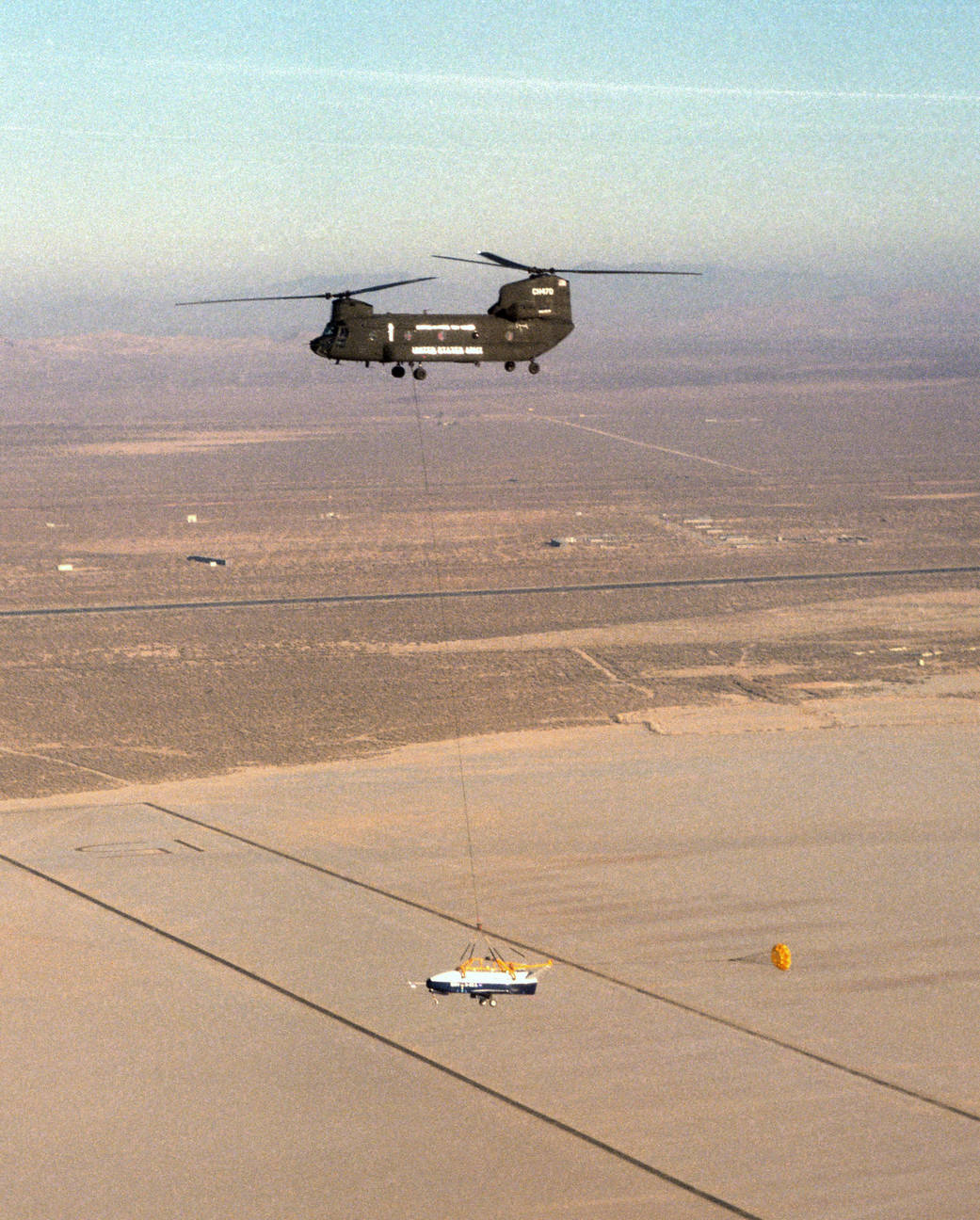 The X-40 sub-scale technology demonstrator and its U.S. Army CH-47 helicopter mothership fly over Rogers dry lakedbed.