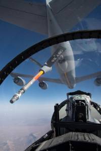 View from cockpit of F-15D aircraft with clouds below and aircraft visible immediately overhead