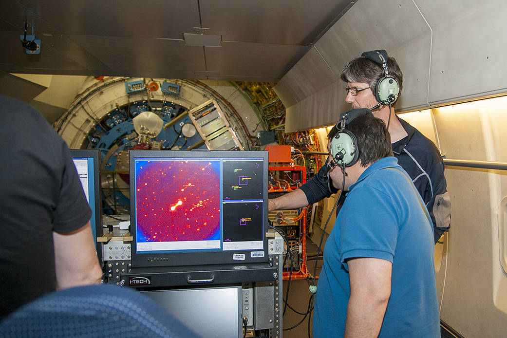 Astronomers smile while looking at data from SOFIA’s telescope.