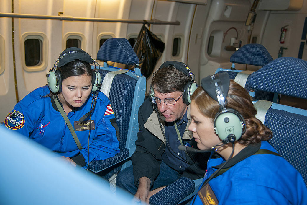 Three people inside of the SOFIA aircraft during a flight.