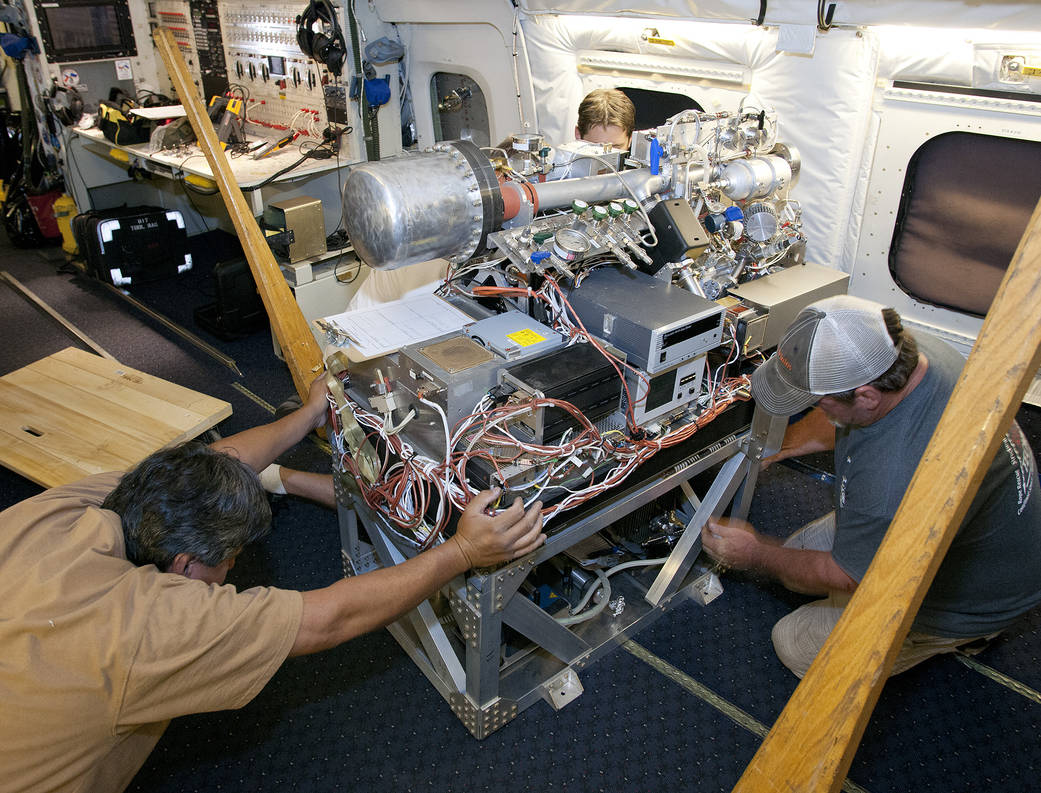 Scientists and technicians ready an instrument rack for mounting in NASA's DC-8 flying laboratory in preparation for a complex m