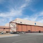A large hanger with a split 225 X 50-foot door and metal staircases on both sides. To the right of the hangar is a smaller attached section of the structure for support staff.