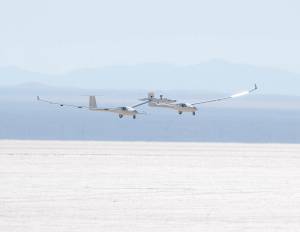 The one-third scale twin-fuselage towed glider glides in for landing on Rogers Dry Lake.
