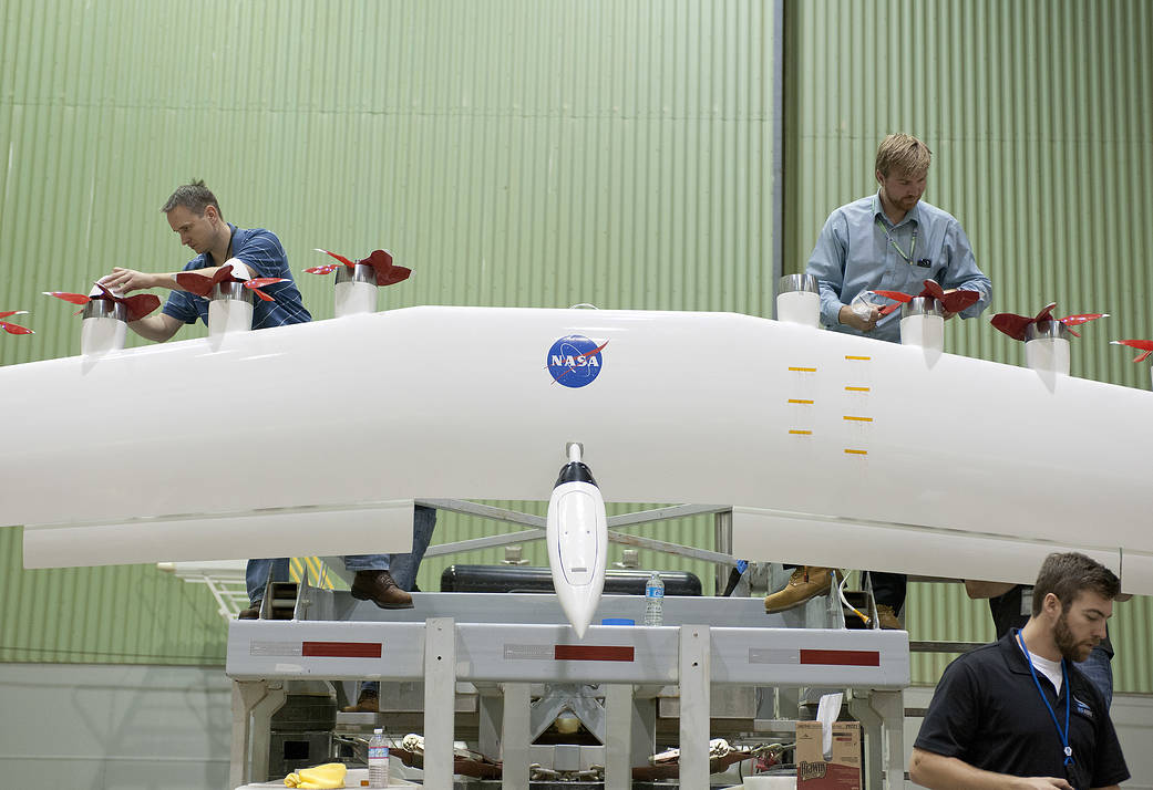 Engineers work on a modified wing equipped with electric motors