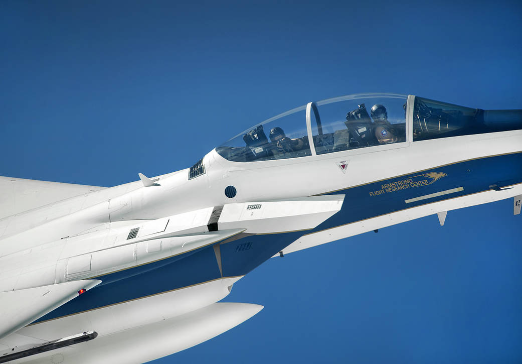Closeup of F-15D chase plane showing pilot in cockpit against blue sky