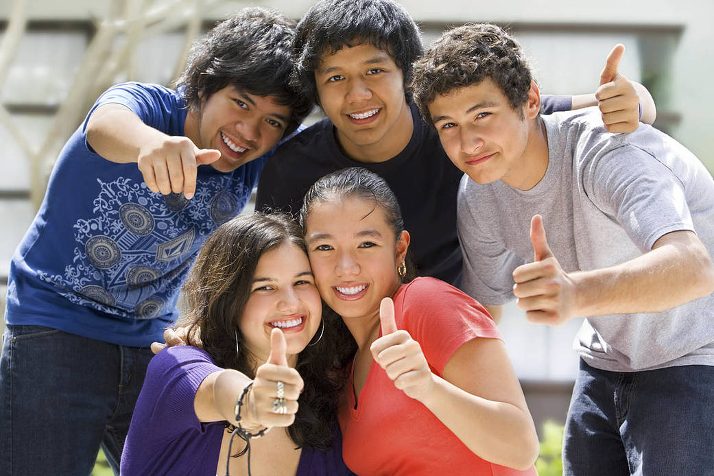 5 Students smiling at camera with their thumbs up.