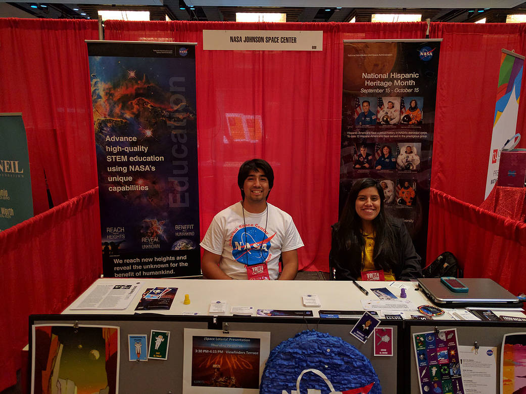 NASA interns Sergio Sandoval and Nancy Villegas sit in a booth at a conference