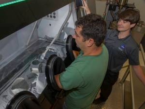 Marshall Center engineers Jim Lydon, left, and Zach Jones work on a recently 3-D printed rocket part.