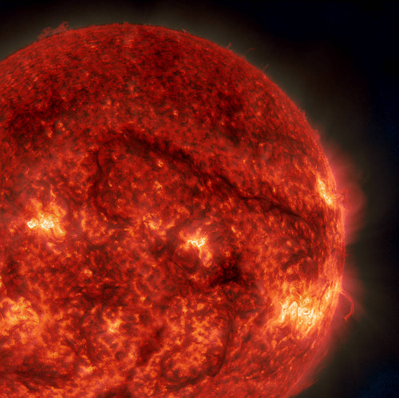 A dark snaking line shows a filament of solar material hovering above the sun's surface.