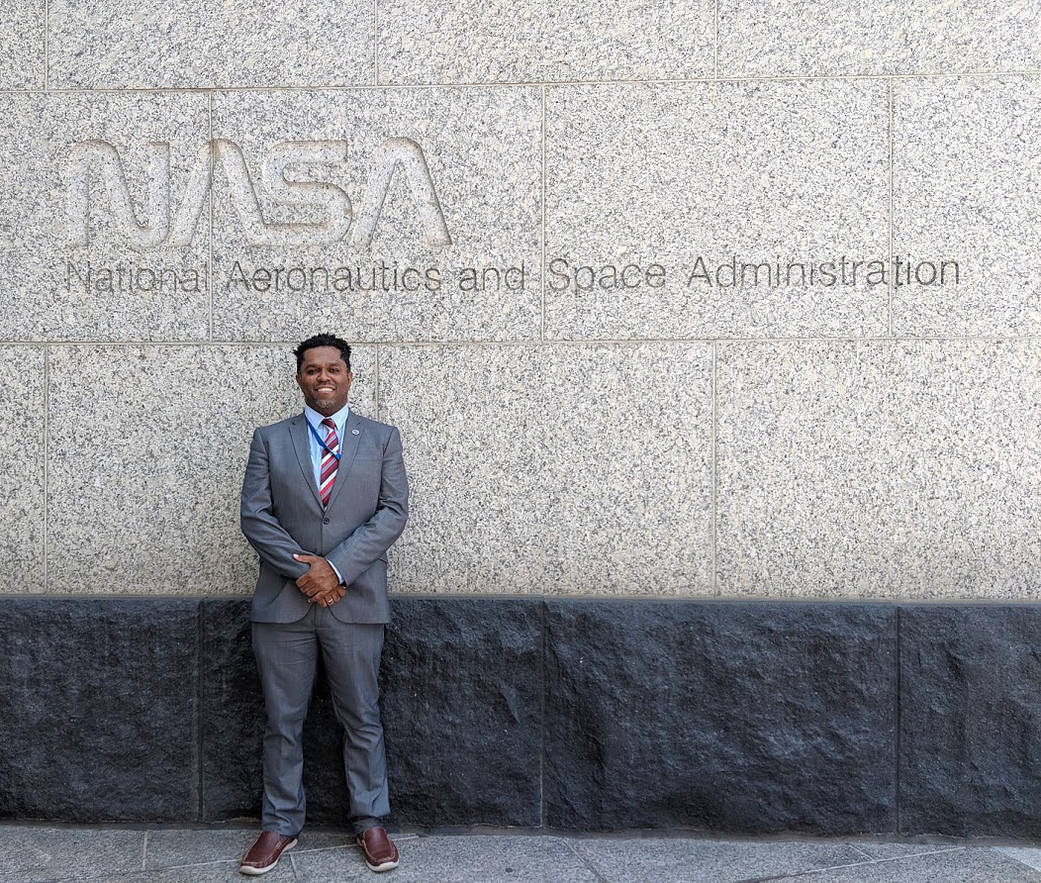 El científico Emil Cherrington delante del logotipo original de la NASA, también conocido en inglés como el "gusano".