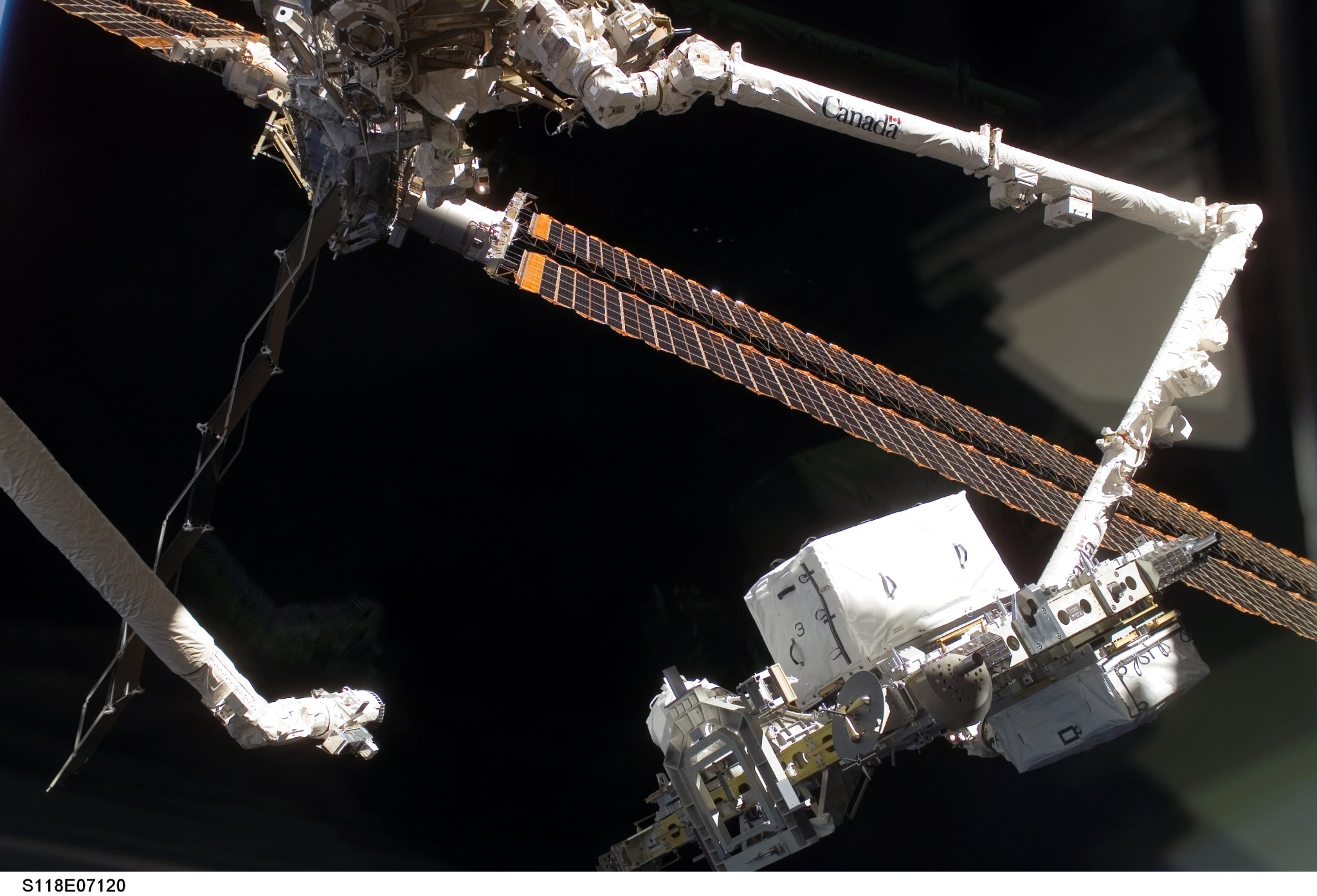 Space shuttle Endeavour's robotic arm (left) moves away following the hand-off of the External Stowage Platform-3 (ESP-3) to the International Space Station's Canadarm2 robotic arm during the STS-118 and Expedition 15 missions on Aug. 14, 2007. The Canadarm2 would install the ESP-3 on the station's Port-3 truss segment.