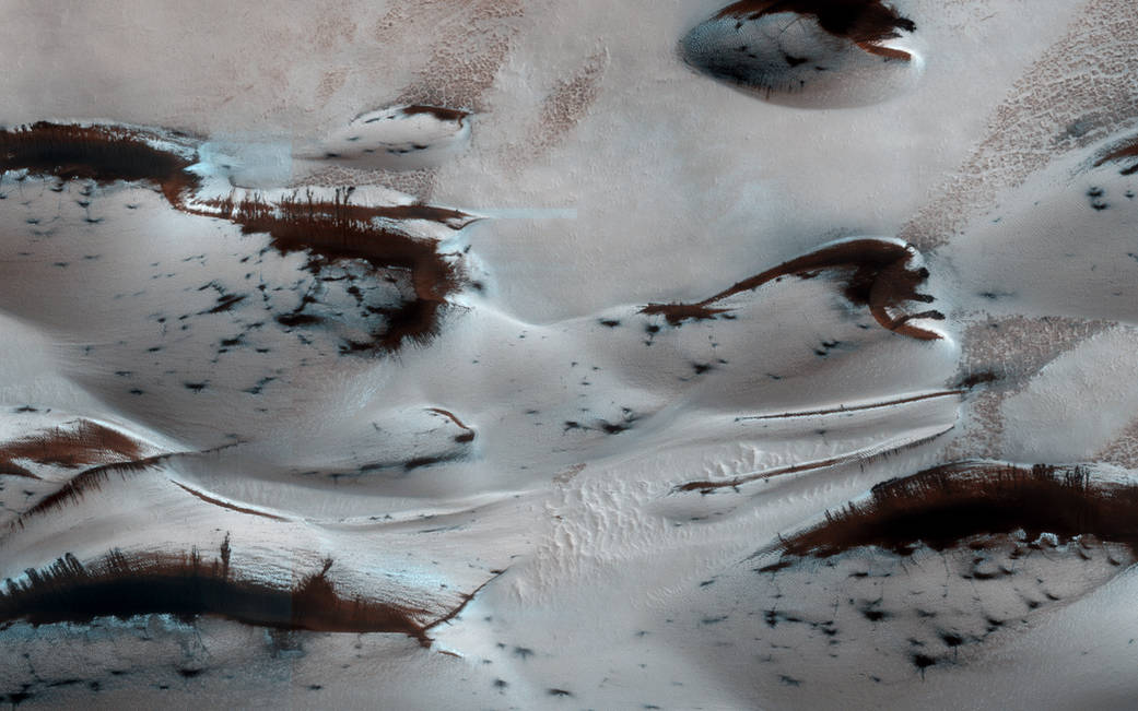 Light colored sandy surface with dark dunes throughout