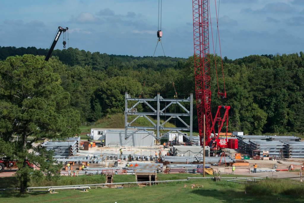 A crane positions the first steel piece for twin towers of a 215-foot-tall structural test stand for NASA's Space Launch System.