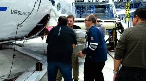 Four men loading a technology payload onto ShpaceShipTwo.