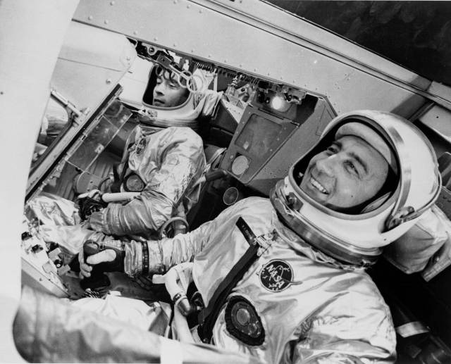 Gemini 3 astronauts Gus Grissom and John Young sit in the Gemini spacecraft simulator