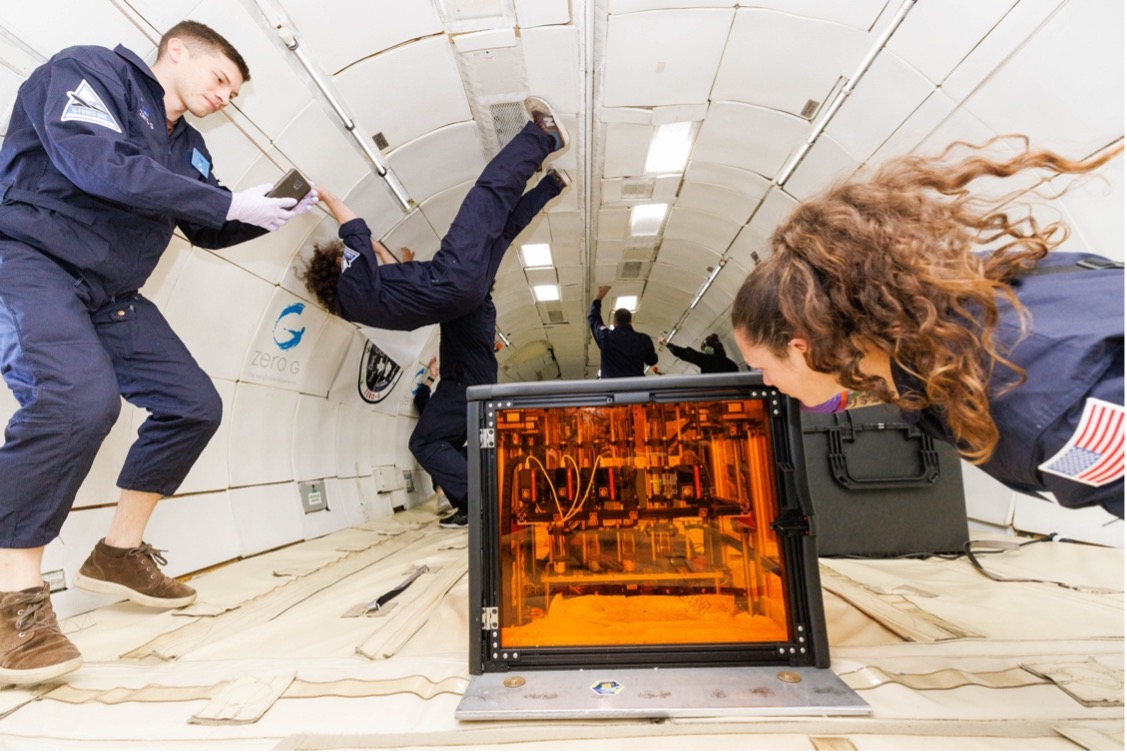 Researchers float in microgravity while checking experiment.