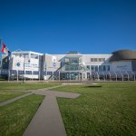 Exterior of the Great Lakes Science Center, with a bright blue sky in the background and green grass in the foreground.