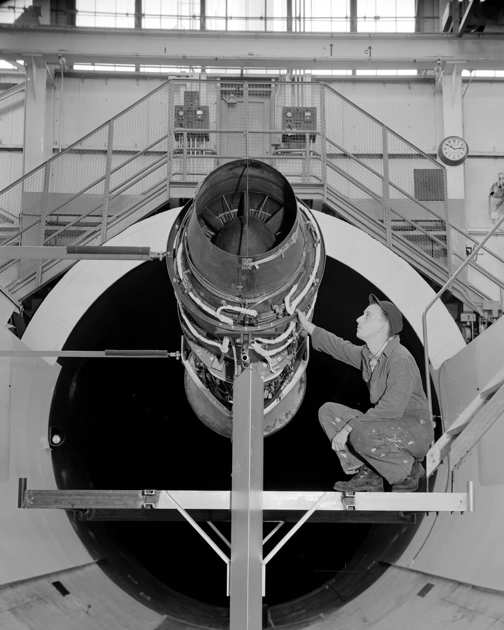 Man crouching with a Pratt & Whitney J57 jet engine