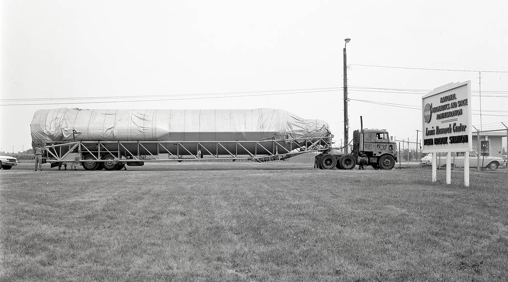 A rocket sits horizontally on a flatbed tractor trailer ready for delivery to a Plum Brook testing facility.