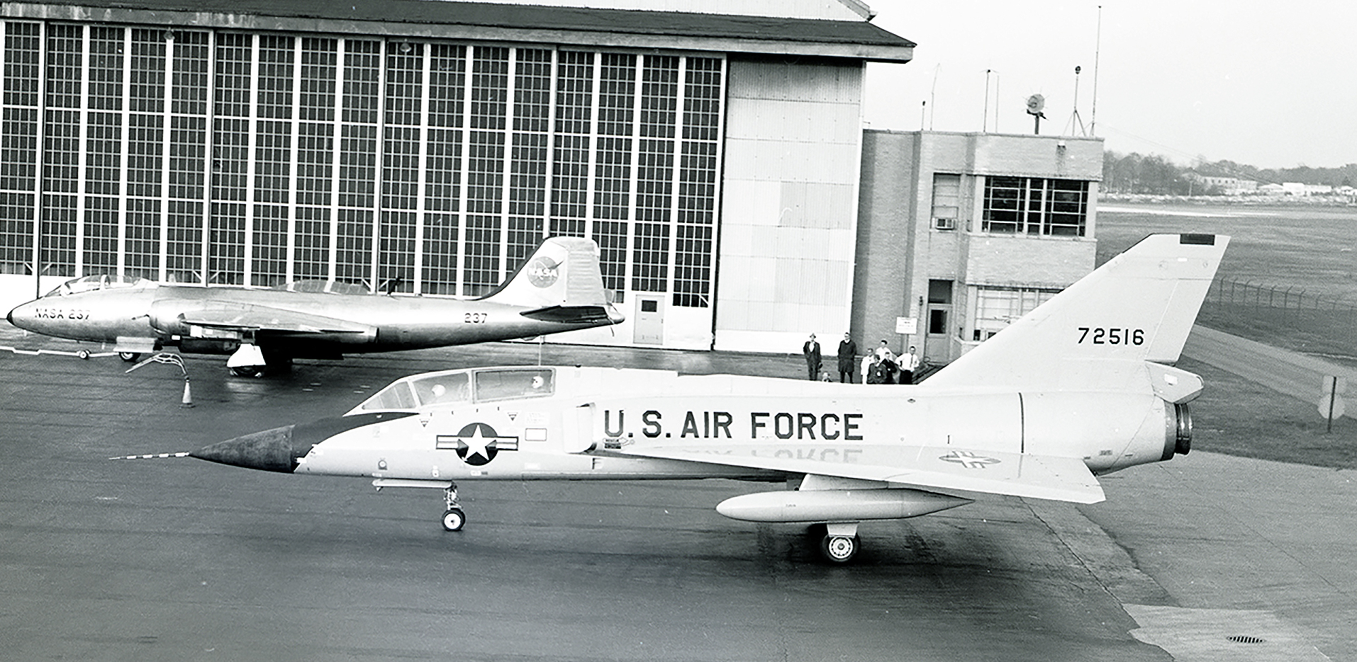 Two military aircraft in front of hangar.