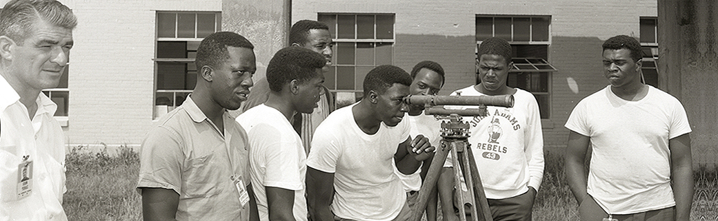 Group of young men with one peering through telescope.