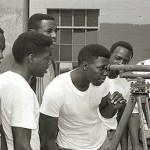 Group of young men with one peering through telescope.