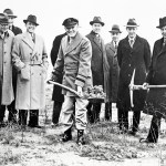 Group of men in field with shovels.