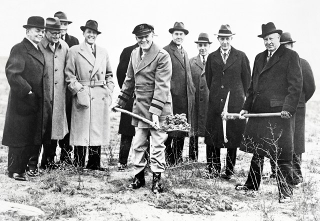 Group of men in field with shovels.