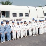 Teacher and students lined up alongside school bus.