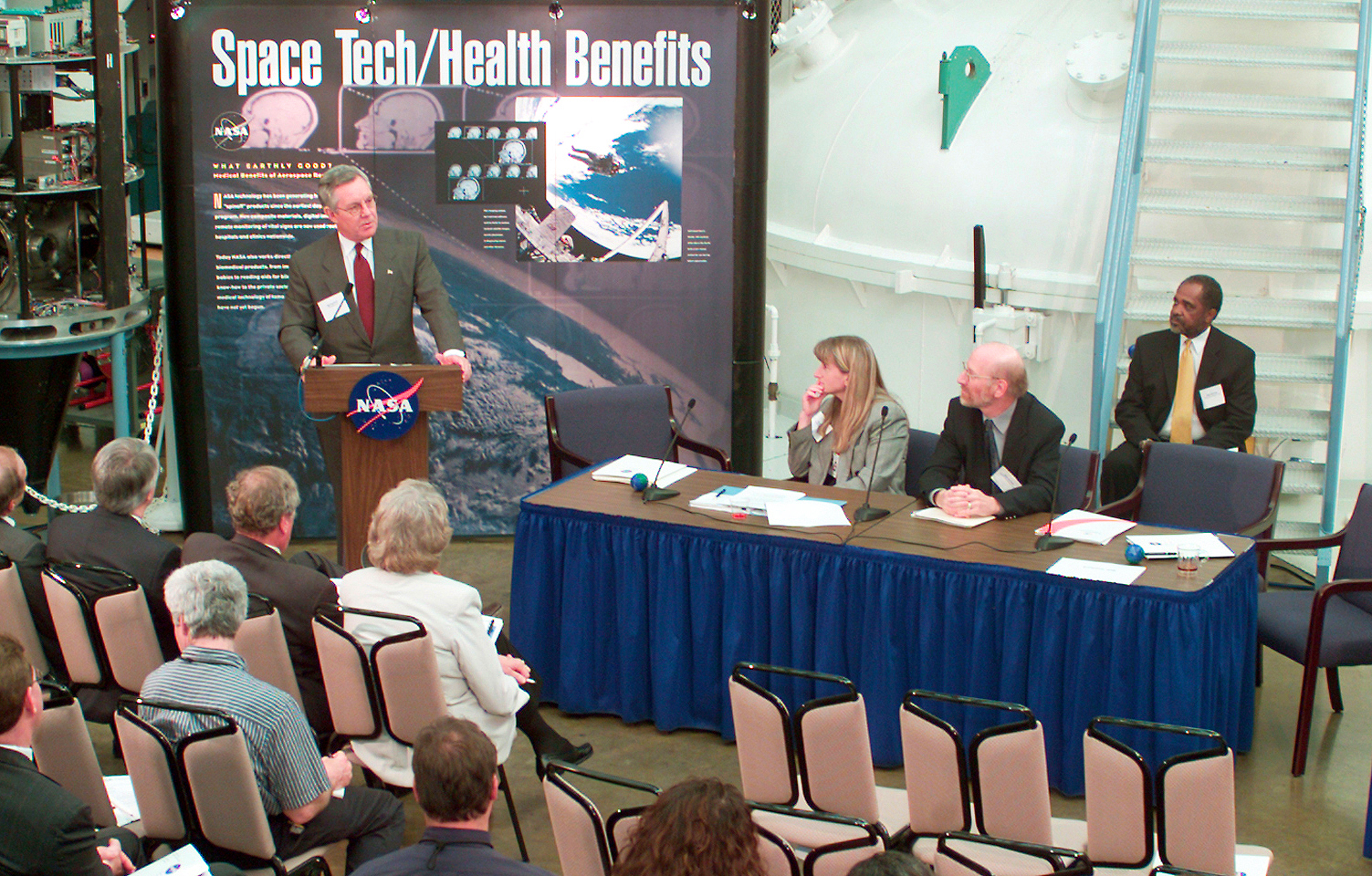 Man at podium addressing panel and attendees.