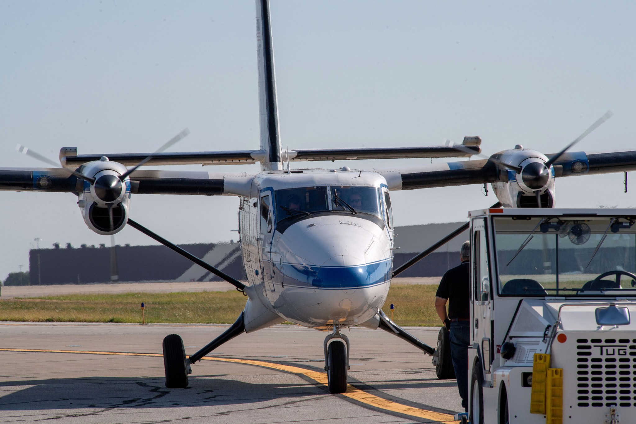 Front view of a twin engine aircraft right behind a service vehicle on an airport taxiway.